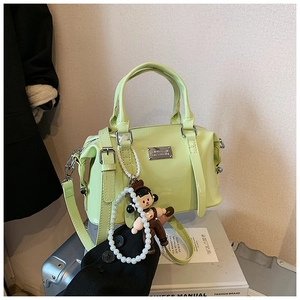 Detail of mint green Boston bag with silver nameplate and cute doll pendant on luggage