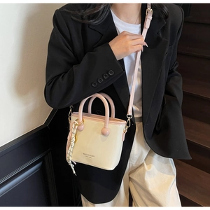 Détail d'un mini sac seau crème avec poignées roses et ornements en corde tressée