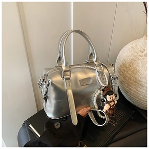 Close-up of silver metallic Boston bag with pearl chain and cartoon doll pendant detail