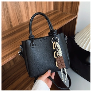 Gros plan du sac seau en cuir grainé noir avec des breloques décoratives et une poignée