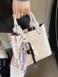Sac seau minimaliste en cuir glacé beige avec nœuds et pendentifs tendance