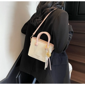 Détail d'un sac seau crème et rose avec ruban rayé et pendentif en métal élégant