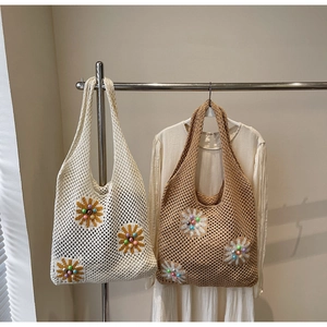Detail of hollow mesh knit tote bag with 3D floral accents and beads for summer vacation