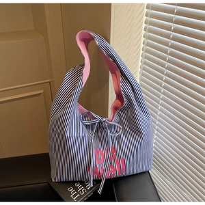 Detail of blue striped canvas tote bag with pink be well print and bow shoulder strap