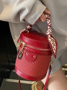 Red cylindrical bucket bag featuring woven contrast and silk scarf wrapped top handle