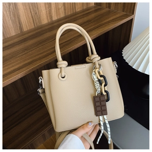 Détail du sac seau beige minimaliste avec texture litchi et charm chocolat