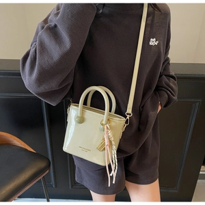 Détail du sac seau en cuir verni vert clair avec poignées et logo imprimé