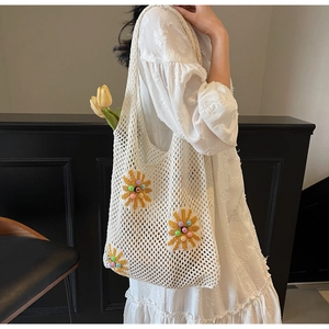 Detailed knit texture of beige crochet beach bag with sunflower pearl embroidery