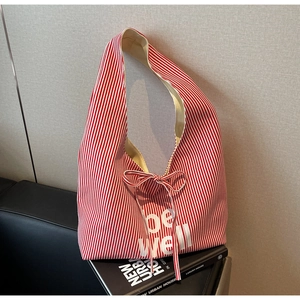 Detail of red and white striped canvas tote bag with bow tie and be well text