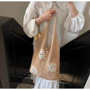 Detail of beige crochet tote bag featuring white floral accents and colorful beads