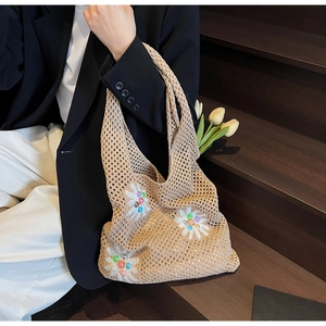 Detail of hand-knitted hollow mesh bag with white daisy patterns and colorful beads