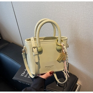 Vue détaillée du sac seau vert olive clair avec breloques dorées et cuir brillant