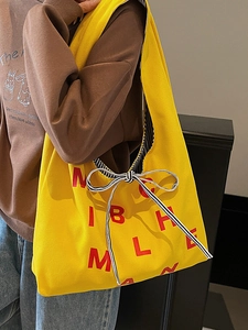 Large yellow canvas tote bag with red letters and striped bow for stylish daily commute