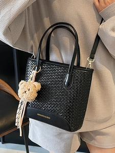 Chic black woven leather tote bag with plush bear charm and adjustable shoulder strap