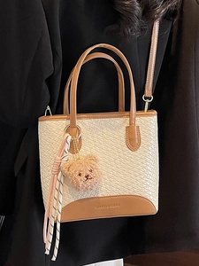 Beige woven texture tote bag with brown leather handles and a cute plush bear charm