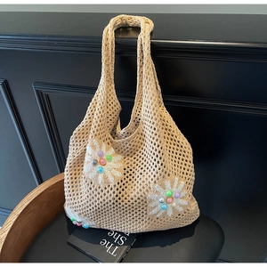 Close-up of beige crochet tote bag with white daisy patterns and colorful resin beads