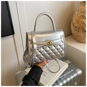 Detalle de bolso Kelly acolchado plateado con cierre de giro dorado y textura de PU