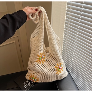 Detail of crochet tote bag with openwork knit and floral beads on cream fabric