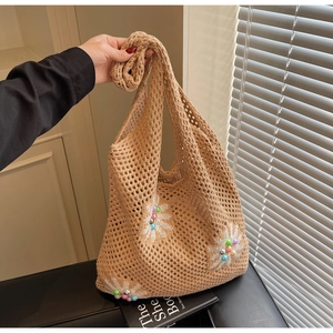 Detail of beige crochet tote bag featuring white daisy embroidery and colorful beads