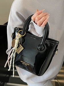 Sac seau élégant en cuir verni noir avec détails dorés et charmants pendentifs