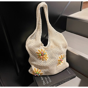 Detail of hand-knitted white tote bag with yellow floral patterns and colorful beads