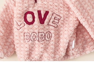Close-up of pink sherpa fleece texture with LOVE BOBO embroidery and zipper detail