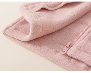 Detailed close-up of pink fleece jacket hem stitching and smooth zipper quality