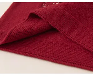 Close-up of the loose-fitting hem on a deep red knitted sweater dress for girls
