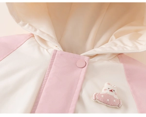 Detail of pink and beige kids hooded jacket with bunny embroidery and snap buttons