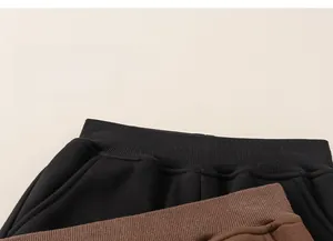 Detail of ribbed elastic waistbands on thick black and brown fleece joggers for kids