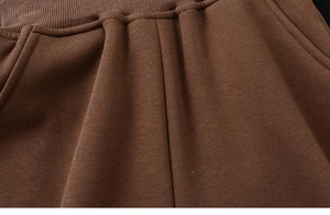 Detail of brown fleece lined joggers showing elastic waistband and side pocket texture
