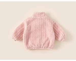 Macro detail of pink fleece kids sweater showing diamond texture and warm ribbed hem