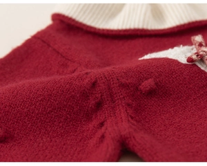 Detail of red knit dress with cream ribbed collar and plush star with plaid bow