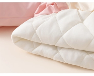 Detailed macro view of white diamond quilted fabric showing stitching and fleece texture