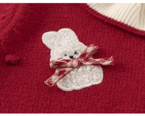 Detailed view of red knitted dress featuring a soft plush bunny patch and bow detail