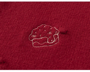 Close-up of cute cupcake embroidery on red knitted fabric for girls dress