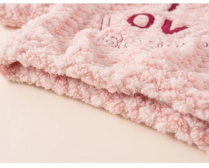Close-up of pink fleece fabric with red letter embroidery and thick plush texture