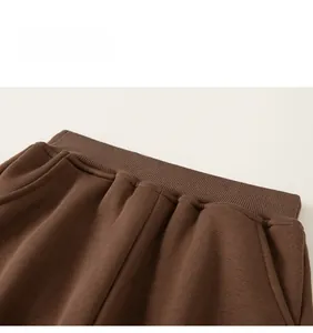 Detailed close-up of brown trousers featuring an elastic ribbed waistband and side pockets