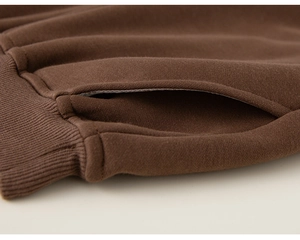 Detail of premium stitching on side pockets and ribbed cuffs of brown winter trousers