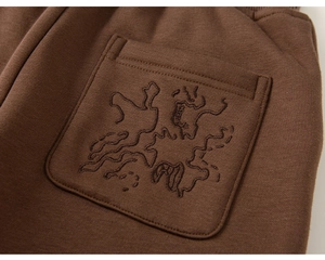 Detail of dark brown thermal trousers featuring high-quality knit texture and back pocket embroidery
