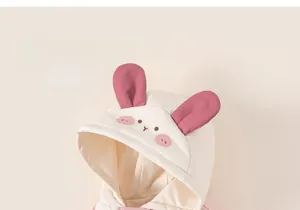 Close-up of cute pink rabbit ear hood with delicate embroidery on warm beige toddler jacket
