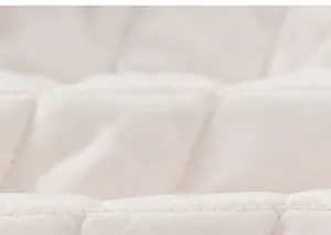Detailed macro view of off-white quilted fabric with reinforced diamond stitching