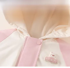 Close-up of kids hooded jacket featuring pink rabbit embroidery and snap buttons