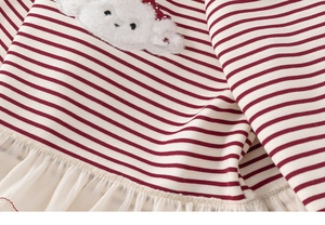 Detail of red and white striped cotton fabric with plush embroidery and tulle hem decoration