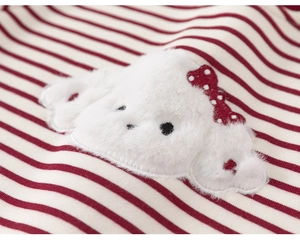 Detailed close-up of plush puppy embroidery with a red bow on a striped knit fabric