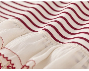 Detail of red and white striped knit fabric with delicate scalloped wave edge stitching