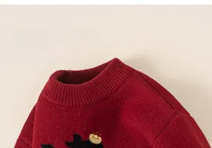 Close-up of red knit sweater featuring ribbed neckline and detailed gold embroidery
