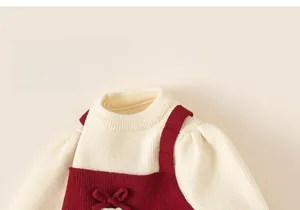 Detail of red knitted girl's dress with cream turtleneck and sweet bow decoration