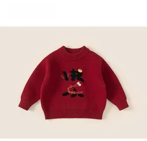 Close-up of red kids sweater with embroidered rabbit, gold ingots and ribbed neckline