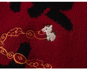 Detail of red knit sweater showing intricate cow embroidery with gold coin motifs